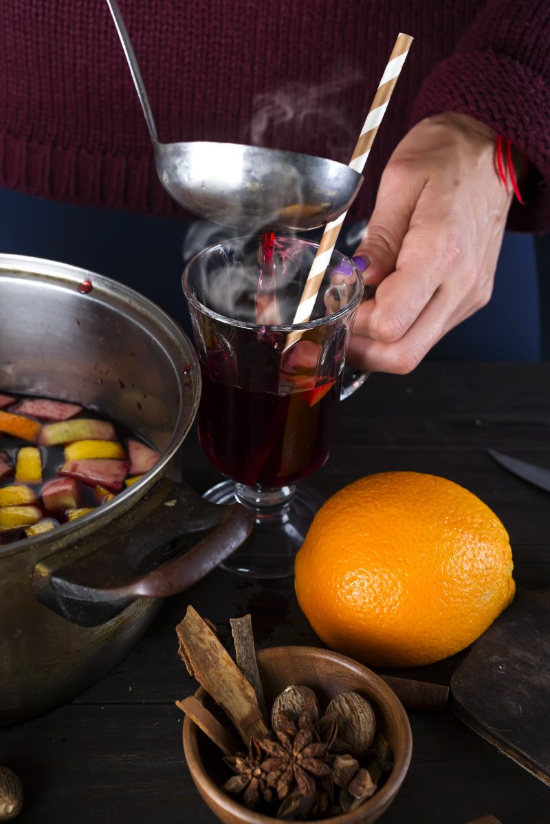 woman pouring hot mulled wine into a glass on a dark background